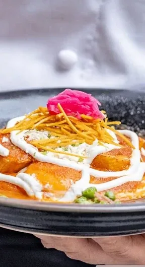 Una preparación con salsa y vegetales sobre un plato oscuro.