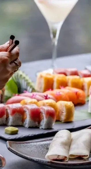 Un surtido de sushi servido junto a una mesa de comensales.